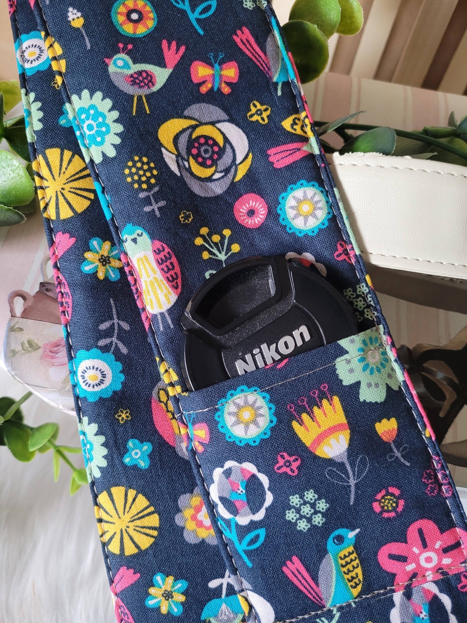 Camera strap cover with lens cap pocket