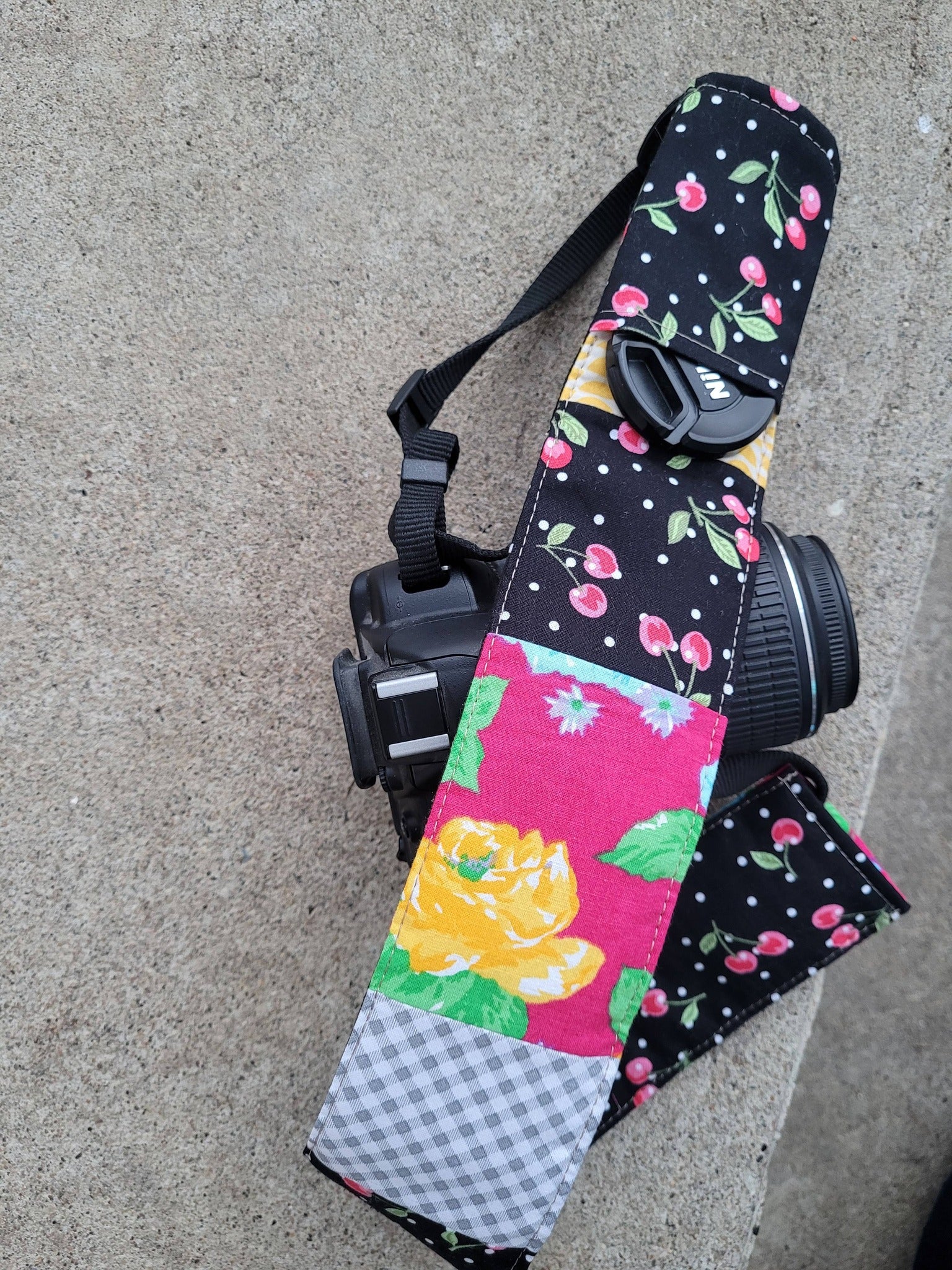 Camera strap cover with lens cap pocket.
